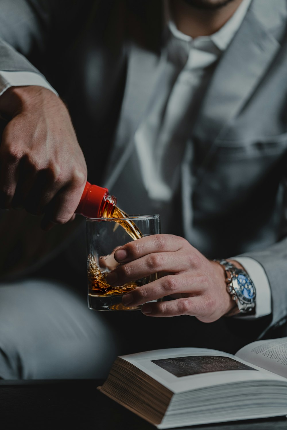 person holding clear drinking glass with brown liquid