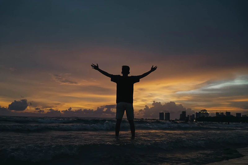 Silhouette of a beautiful UK sugar baby standing on the beach during sunset