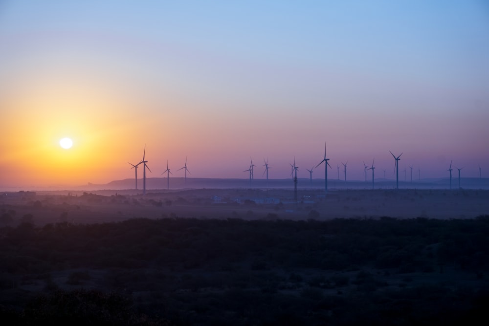 wind turbines on green grass field during sunset