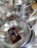 Stacks of stainless steel frying pans with labels are neatly displayed, highlighting their shiny surfaces and sturdy handles.