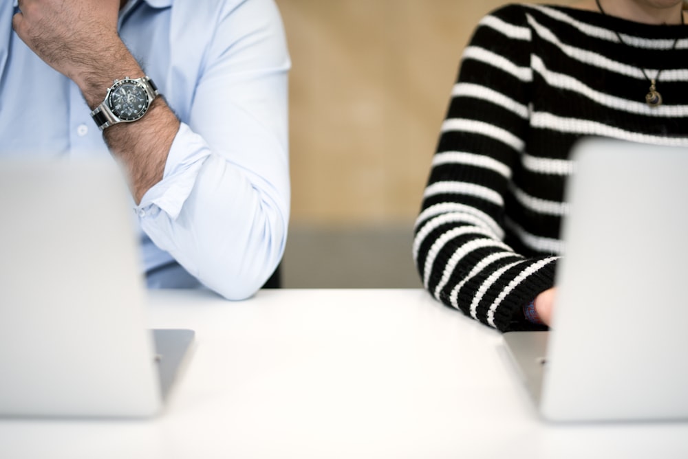 man in white dress shirt sitting beside woman in black and white striped long sleeve shirt