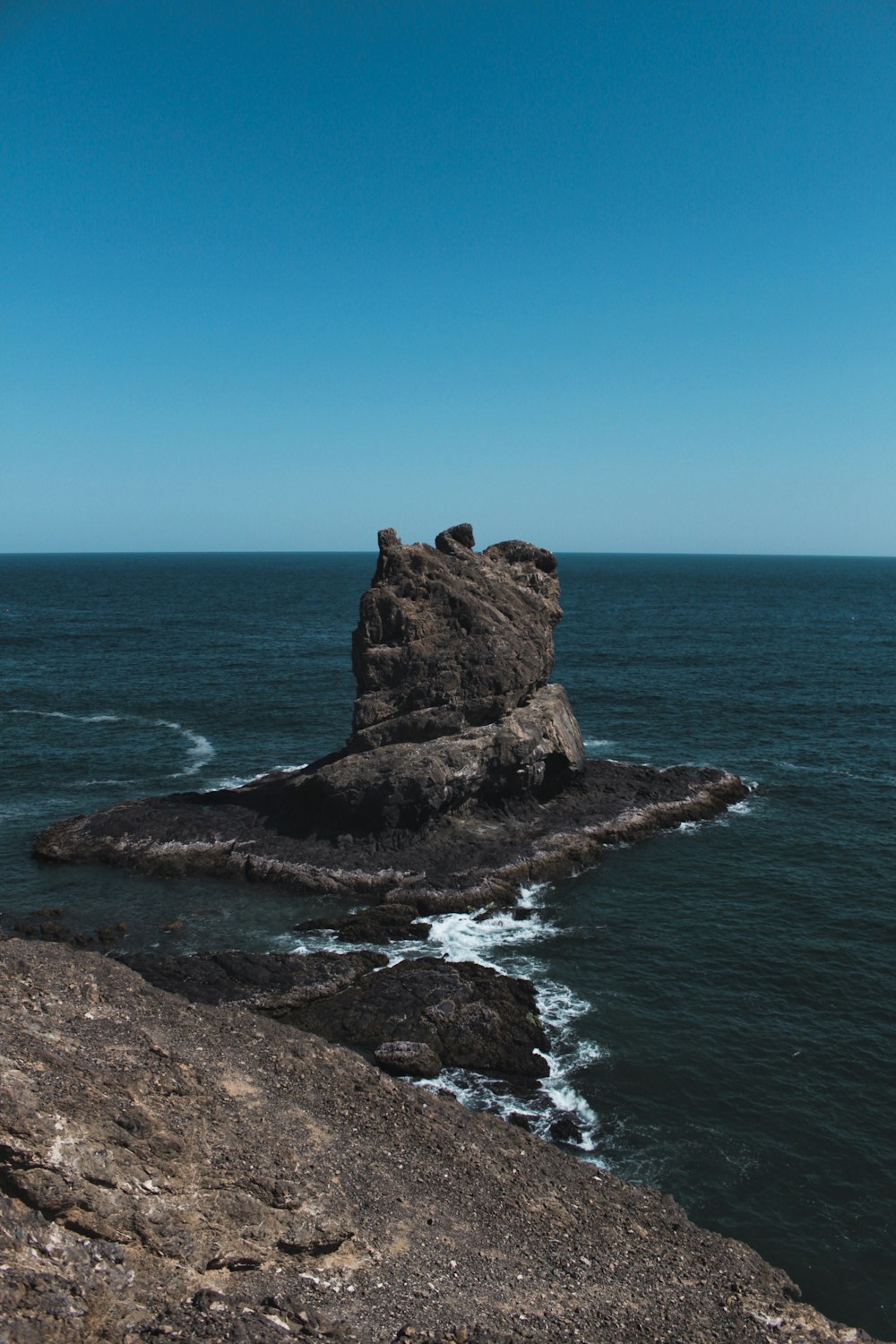 brown rock formation on sea under blue sky during daytime