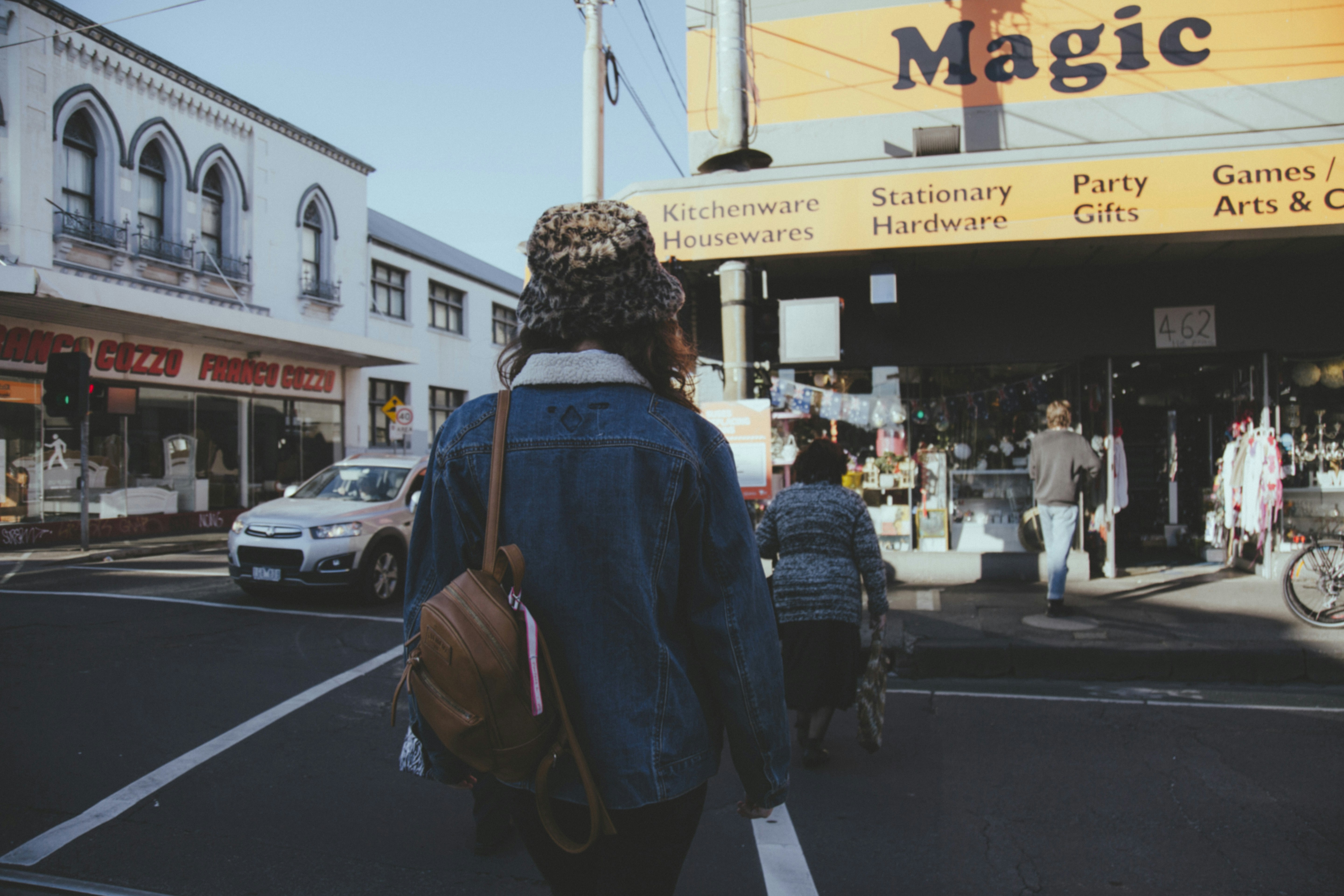 man in blue jacket standing in front of store during daytime