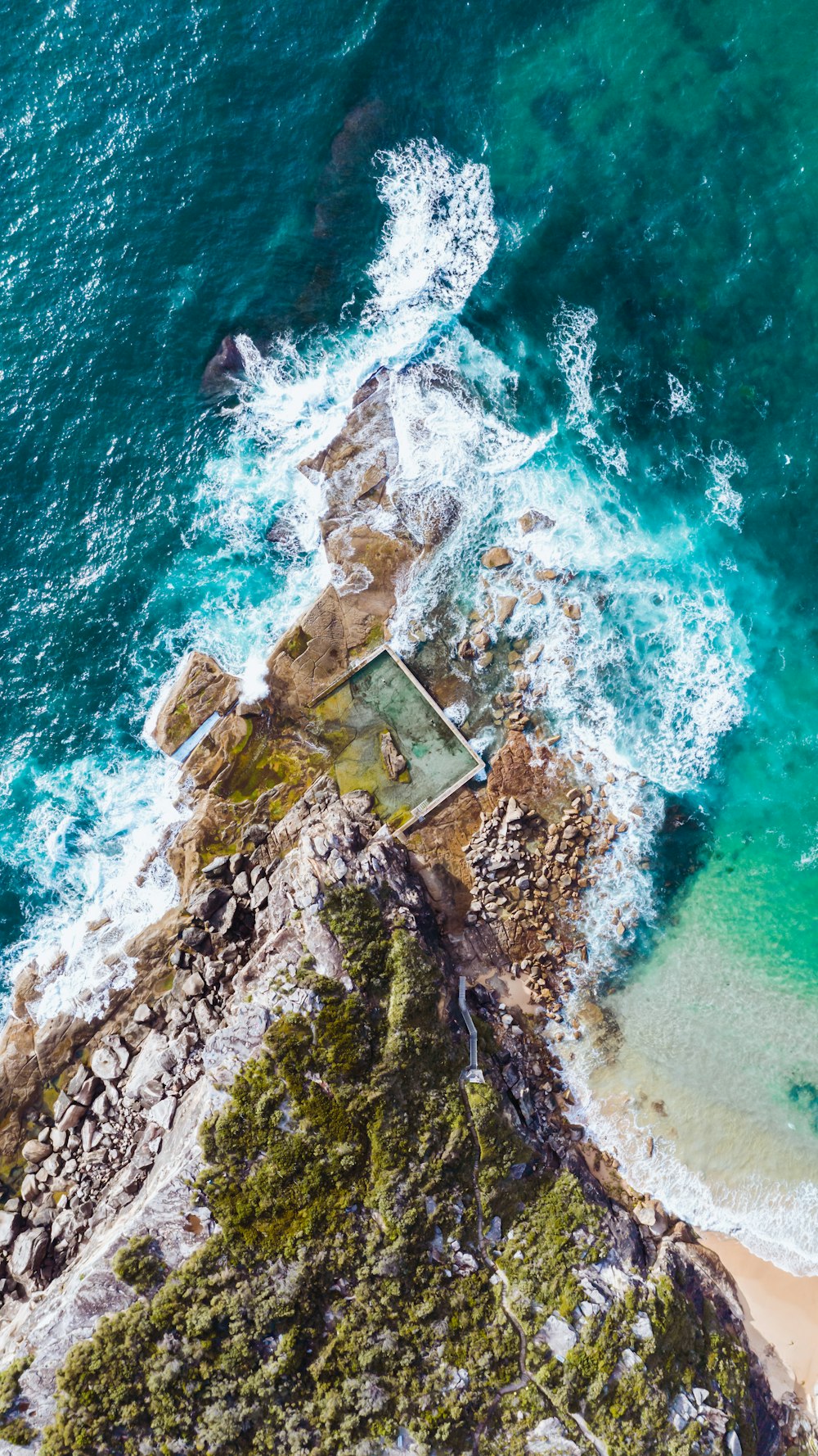 aerial view of brown and white house on brown rock formation beside body of water during