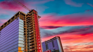 A sleek modern high-rise building in Dubai under construction at sunset.