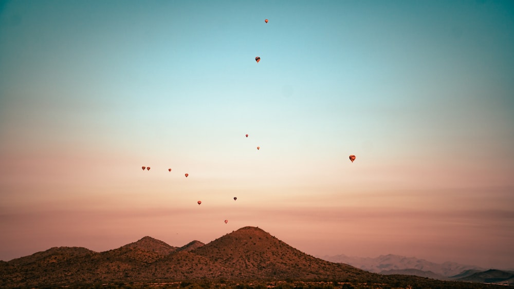 hot air balloons flying over brown mountain during daytime