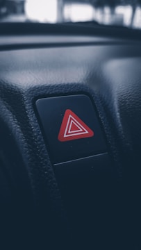A close-up of a hand pressing a red alert button on a digital dashboard.