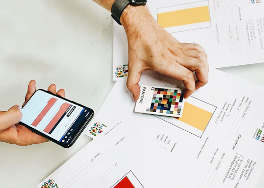 person holding iphone on white printer paper