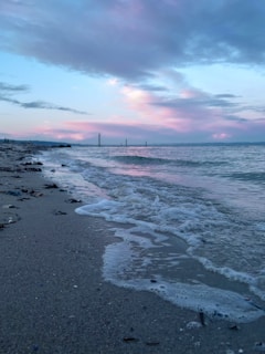 A serene beach at dusk with gentle waves and pastel skies.