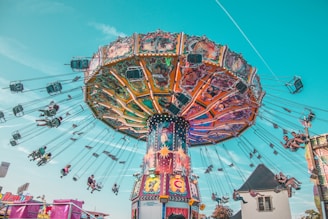 people riding on yellow and red carousel during daytime
