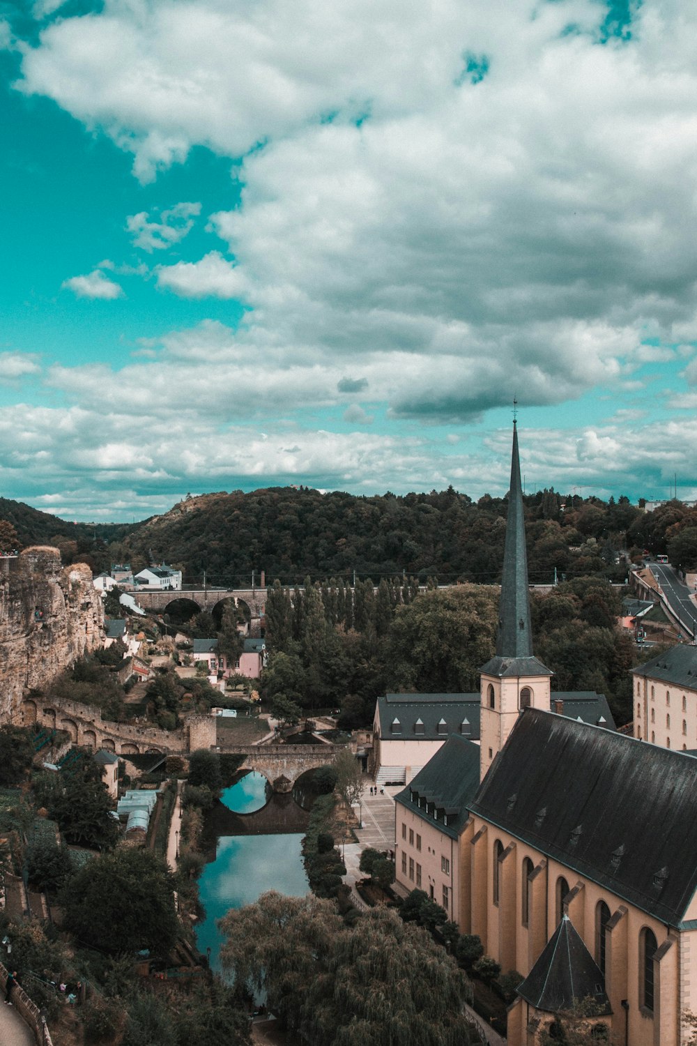 Weißes und graues Betongebäude in der Nähe grüner Bäume unter weißen Wolken und blauem Himmel tagsüber