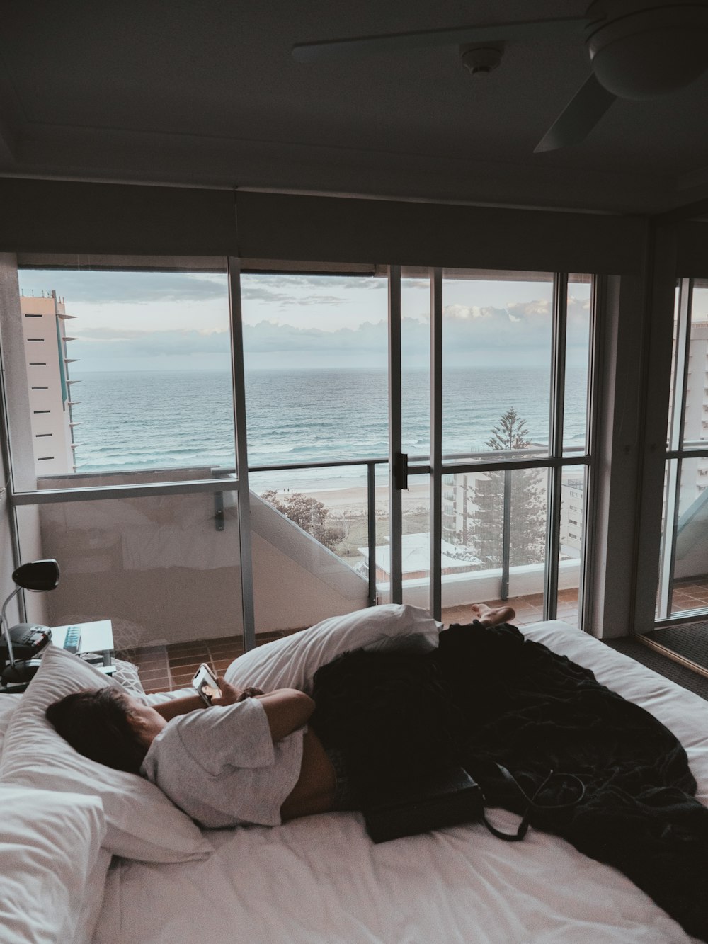 person lying on bed near window