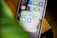 A smartphone screen displaying a folder labeled 'Messages' containing messaging application icons such as WhatsApp, Telegram, Line, WeChat, and Signal. A blurred green plant is visible in the foreground, partially covering the view.