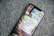 A smartphone resting on a textured fabric surface displays a folder labeled 'Messages' with multiple messaging app icons arranged within. The apps visible are WhatsApp, Telegram, LINE, WeChat, and Signal, each represented by their distinct logos.
