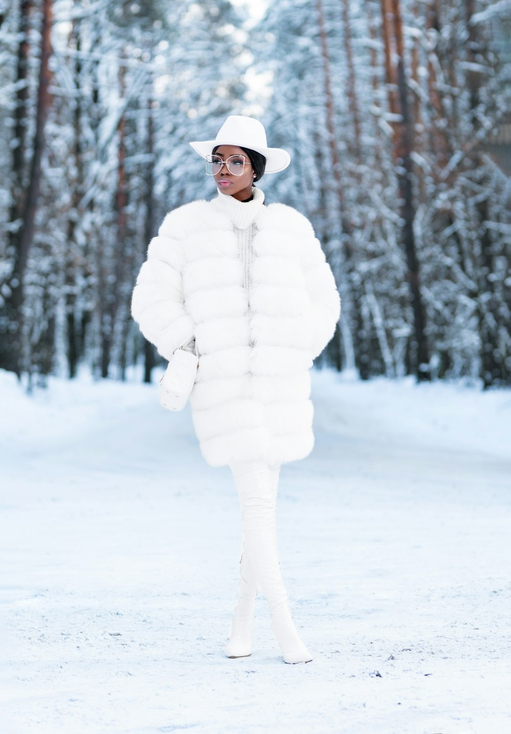 昼間、雪に覆われた地面に立つ白衣の女性