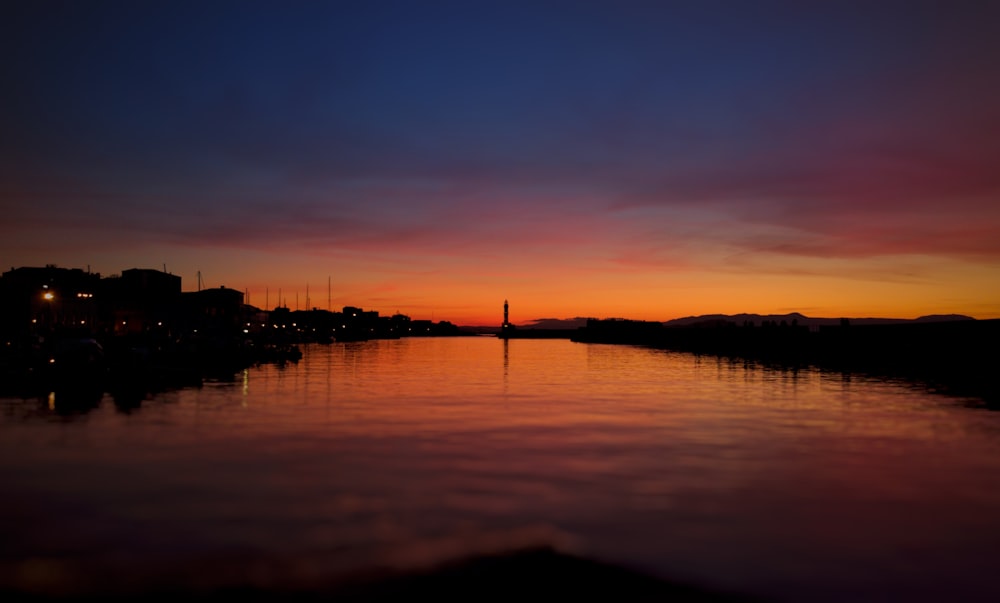 silhouette of buildings near body of water during sunset