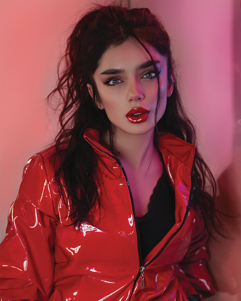 woman in red blazer standing near pink wall