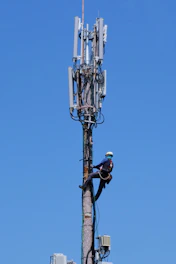 Technician safely working at height on a telecom tower.