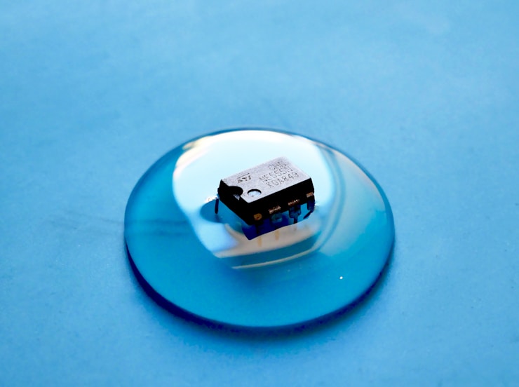 An NE555 timer IC near a blob of water placed on a silicone mat.