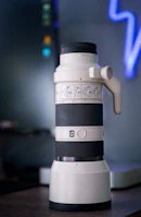 A photographer adjusting a camera lens next to a large monitor displaying vivid photos.