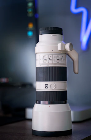 A photographer adjusting a camera lens next to a large monitor displaying vivid photos.