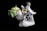 Porcelain figurine depicting two white birds with intricate details, perched among colorful flowers, next to a green ceramic teapot with a yellow lid. The composition is set against a dark background, showcasing the smooth and glossy finish of the ceramics.