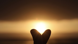 A dreamy golden sunset scene with soft glowing hearts floating gently over a romantic couple silhouette.