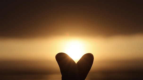 A dreamy golden sunset scene with soft glowing hearts floating gently over a romantic couple silhouette.