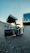 A professional technician installing a security camera on a commercial building exterior at sunset.