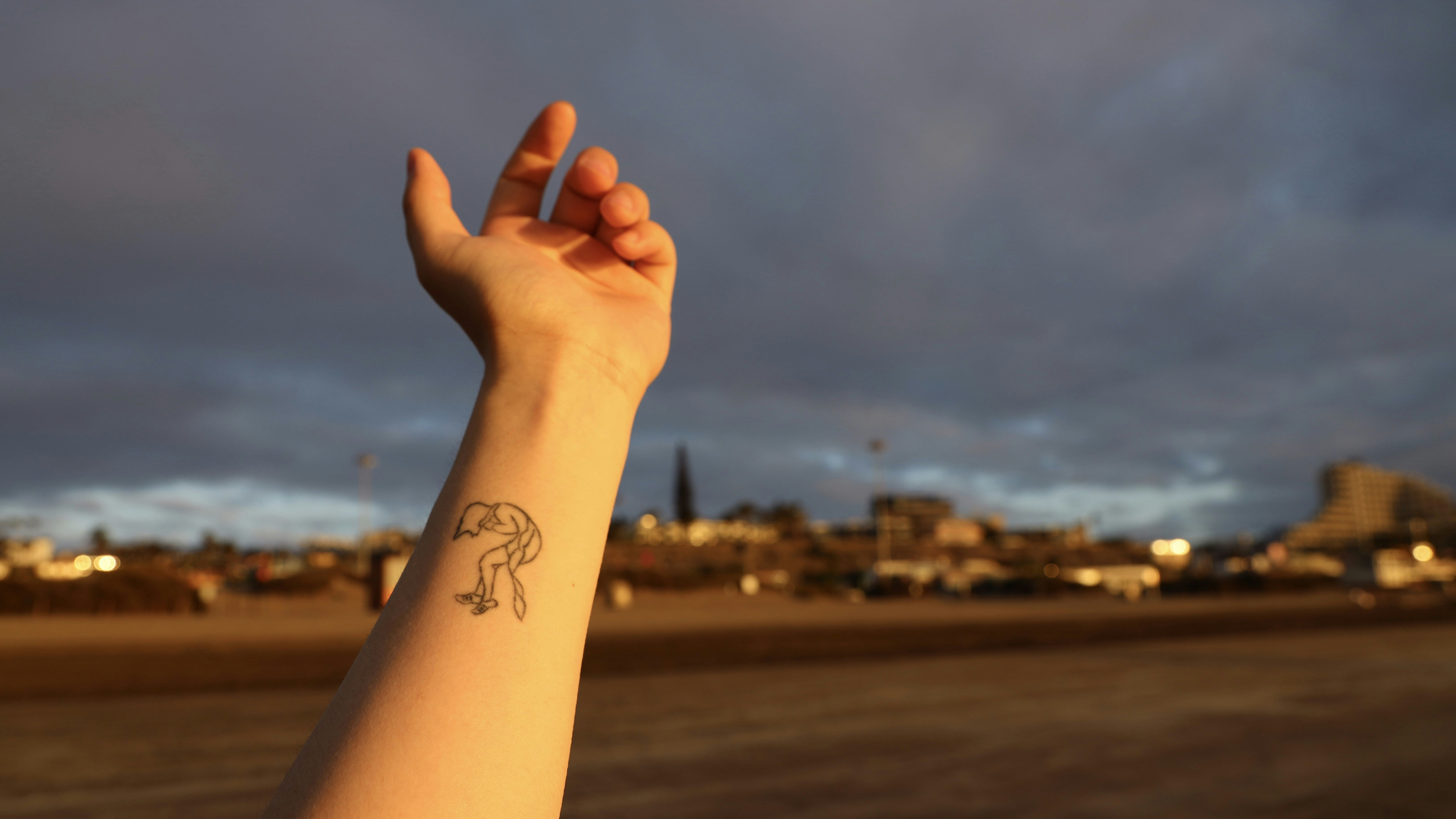 person with black tattoo on left hand
