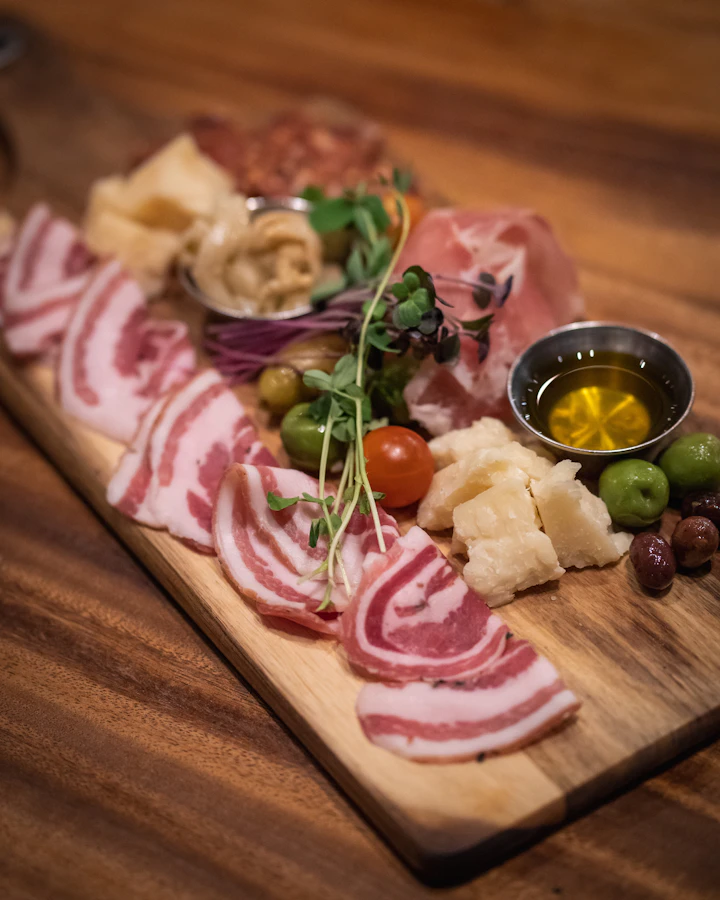 A salumi board with olives, parmesan, and oil