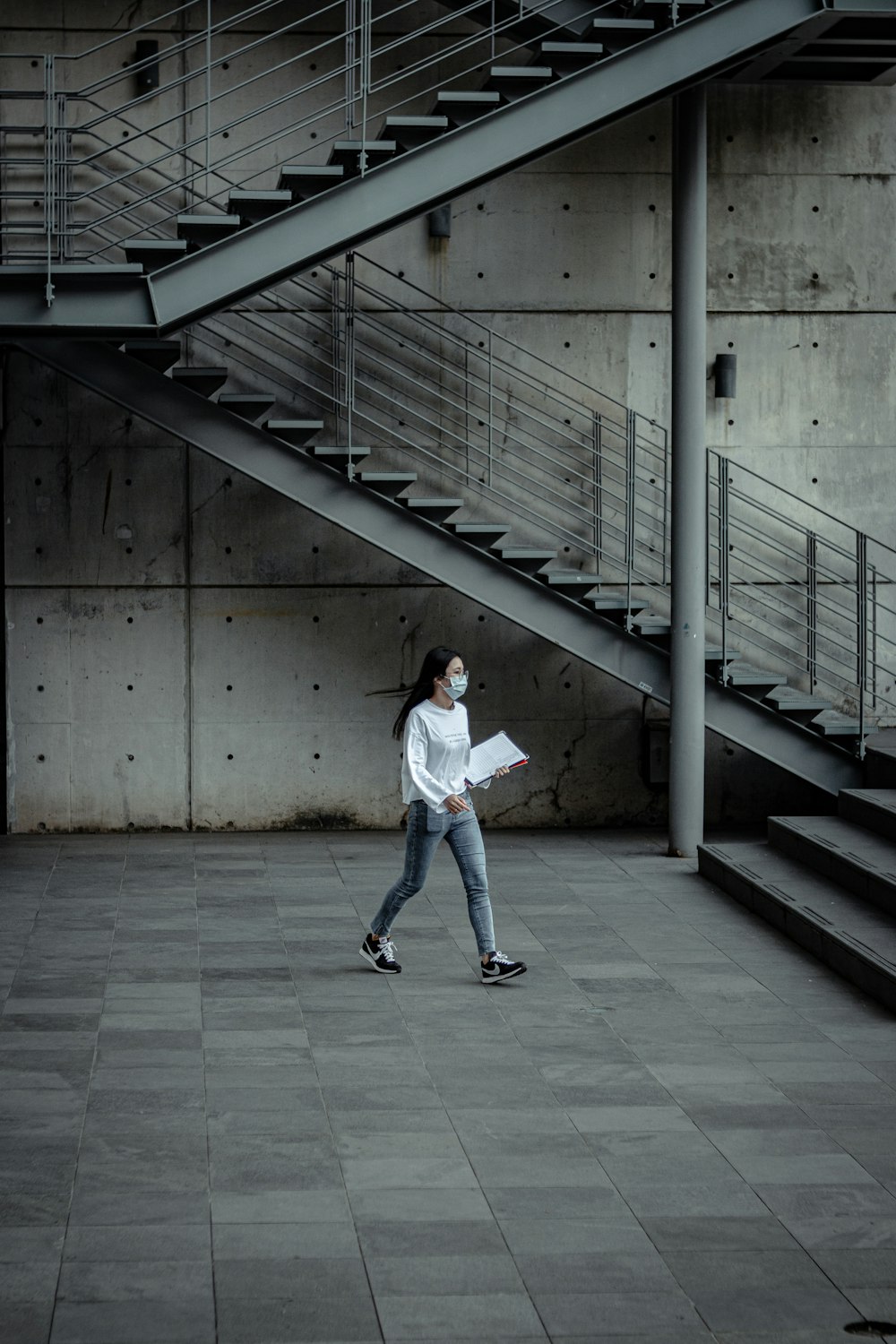 woman in white long sleeve shirt and blue denim jeans walking on gray concrete floor