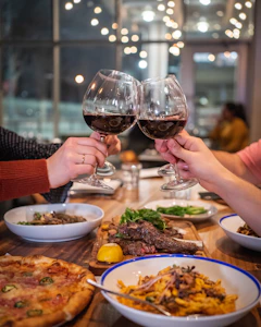 Glasses of red wine clinking over dinner