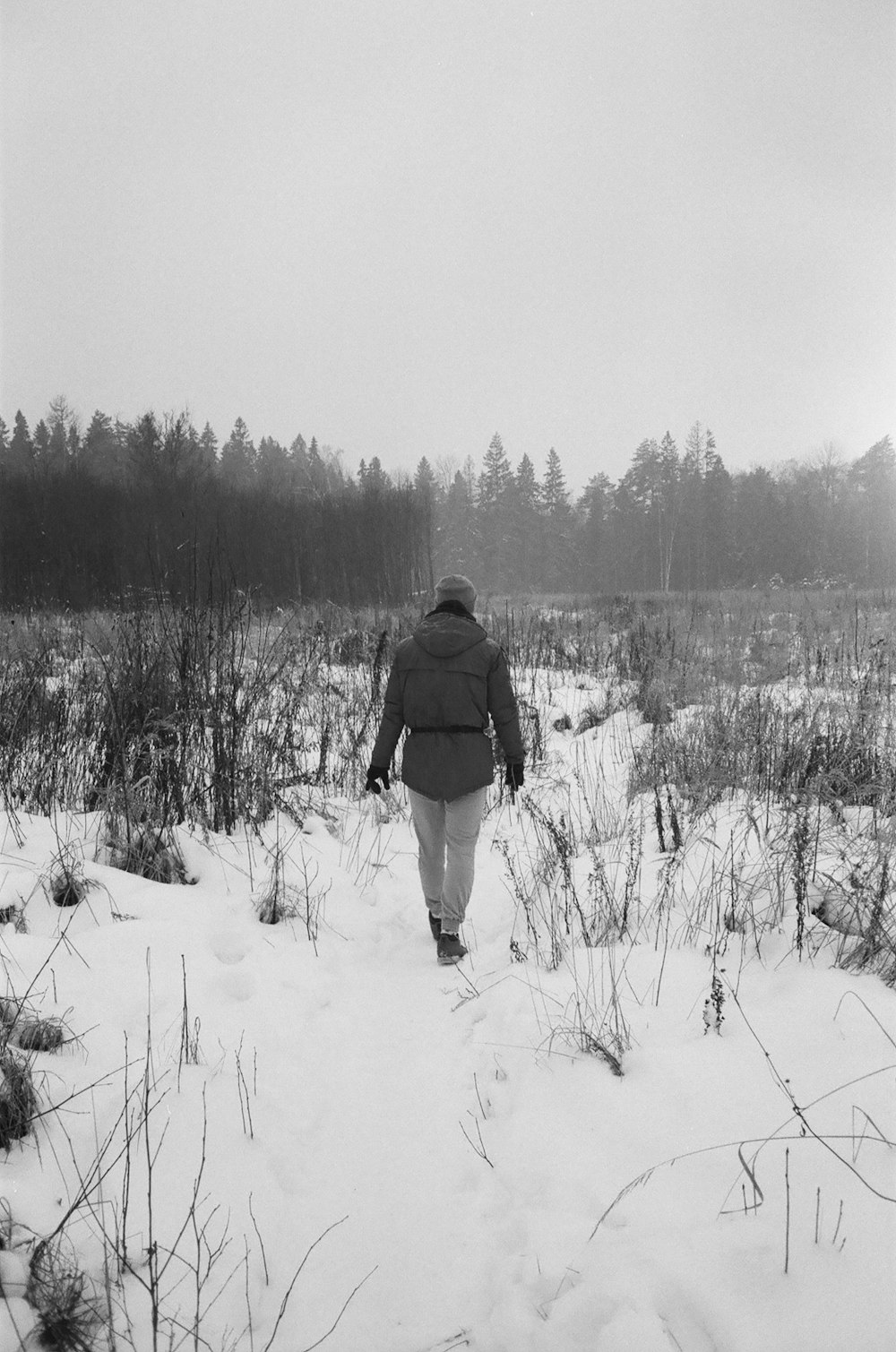 man in black jacket walking on snow covered field during daytime