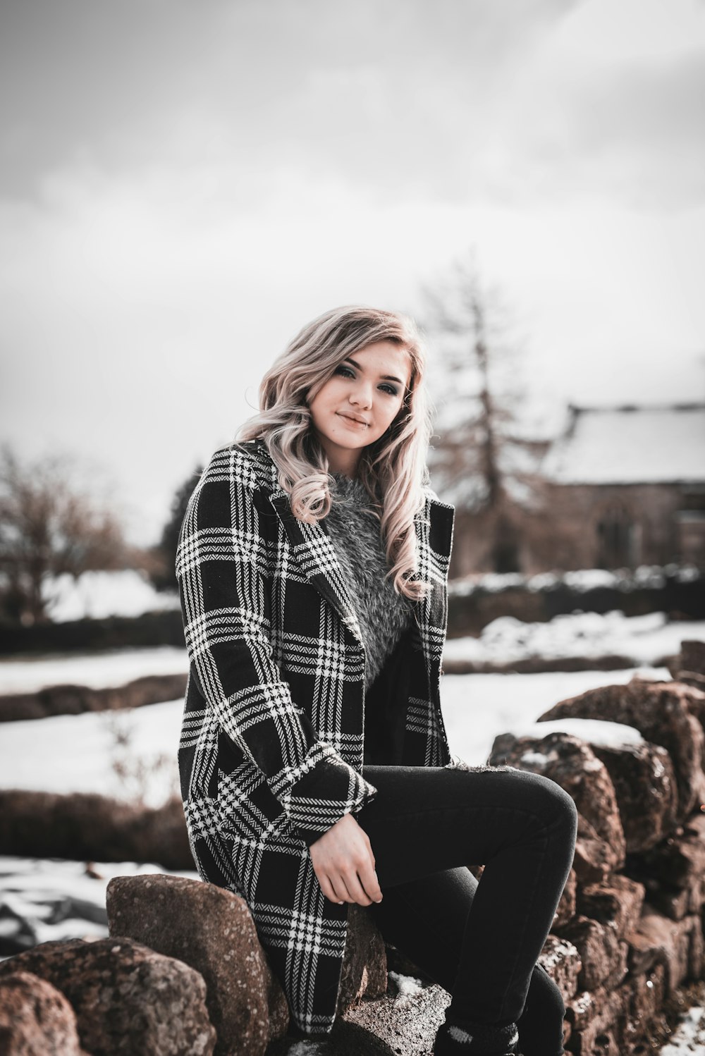 woman in black and white checkered coat sitting on brown wooden bench during daytime