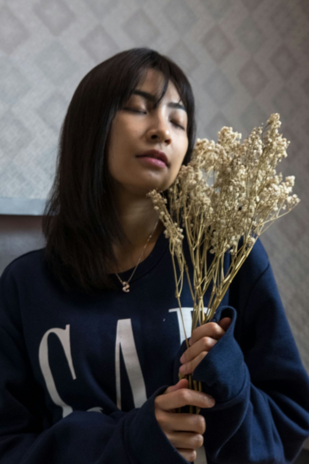 woman in blue and white long sleeve shirt holding yellow flower