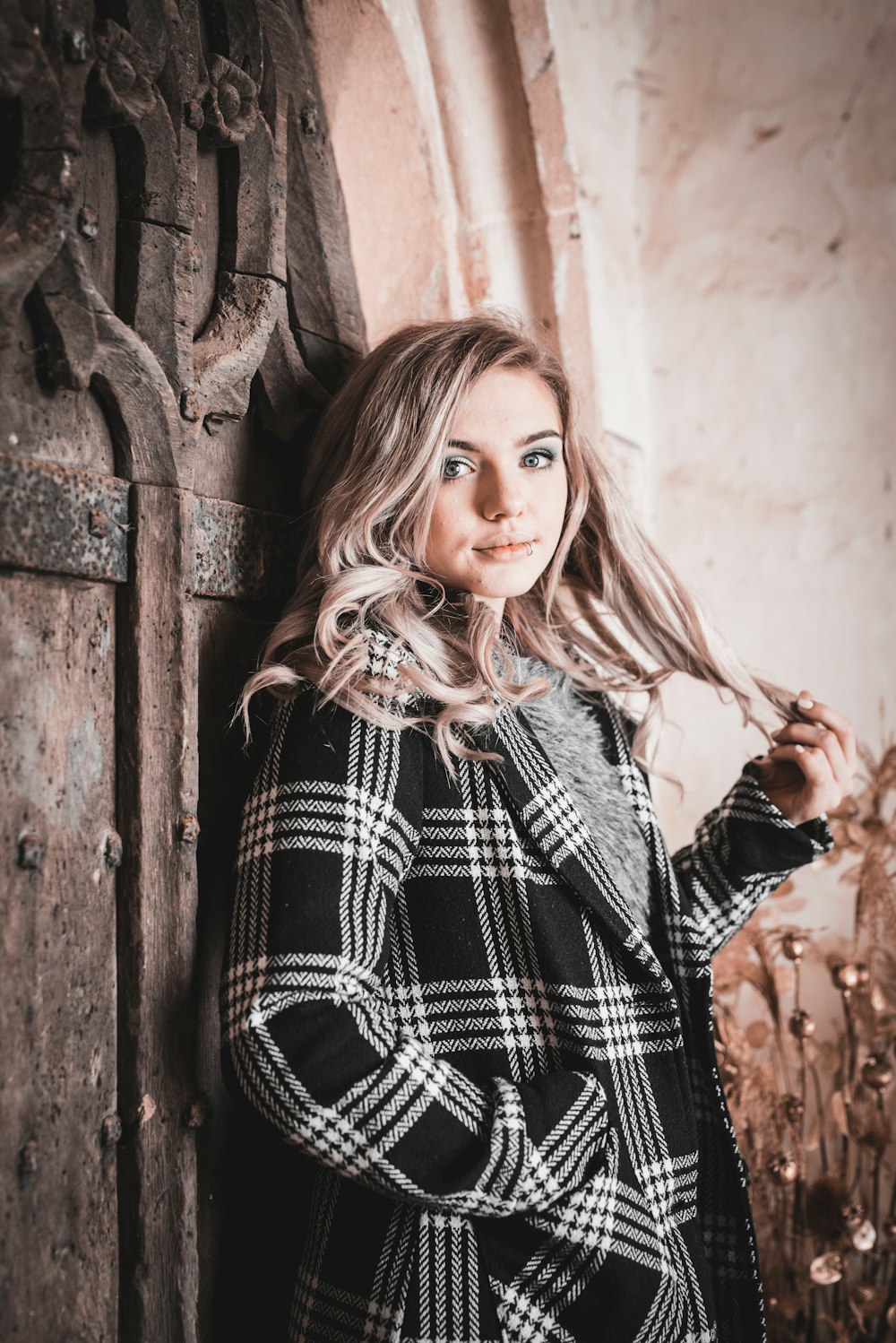 woman in black and white plaid long sleeve shirt standing beside brown wooden wall