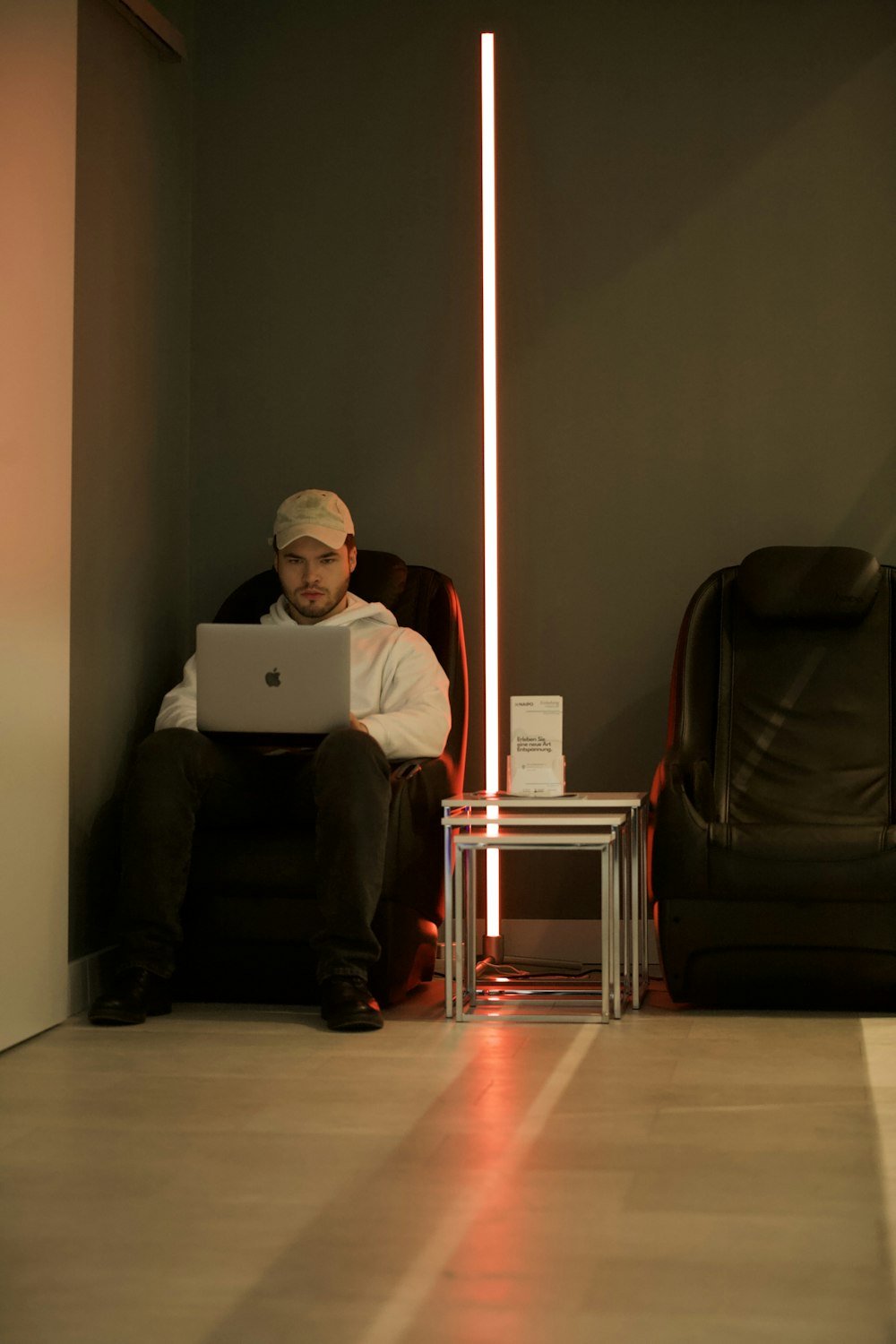 man in white dress shirt sitting on black leather armchair using macbook