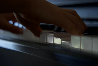 Close-up of Jaiden’s hands gracefully playing piano keys in a dimly lit setting.