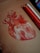A detailed drawing of a human anatomical heart on brown paper with an emphasis on red and white highlights. Next to the drawing are several colored pencils, ranging from white to various shades of red and orange.