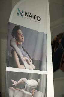 A banner displays a promotional image featuring a person enjoying a neck and shoulder massager. The top part of the banner includes the logo and slogan of the brand Naipo, with the tagline 'Find Well-being'. The model appears to be relaxed and comfortable, reinforcing a sense of tranquility.