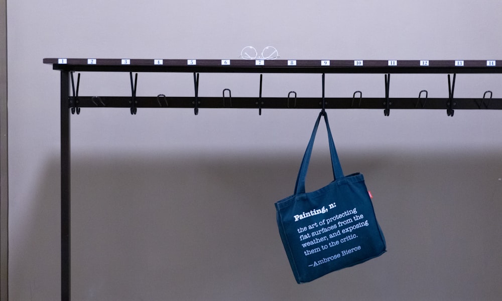 blue tote bag hanging on black metal bar