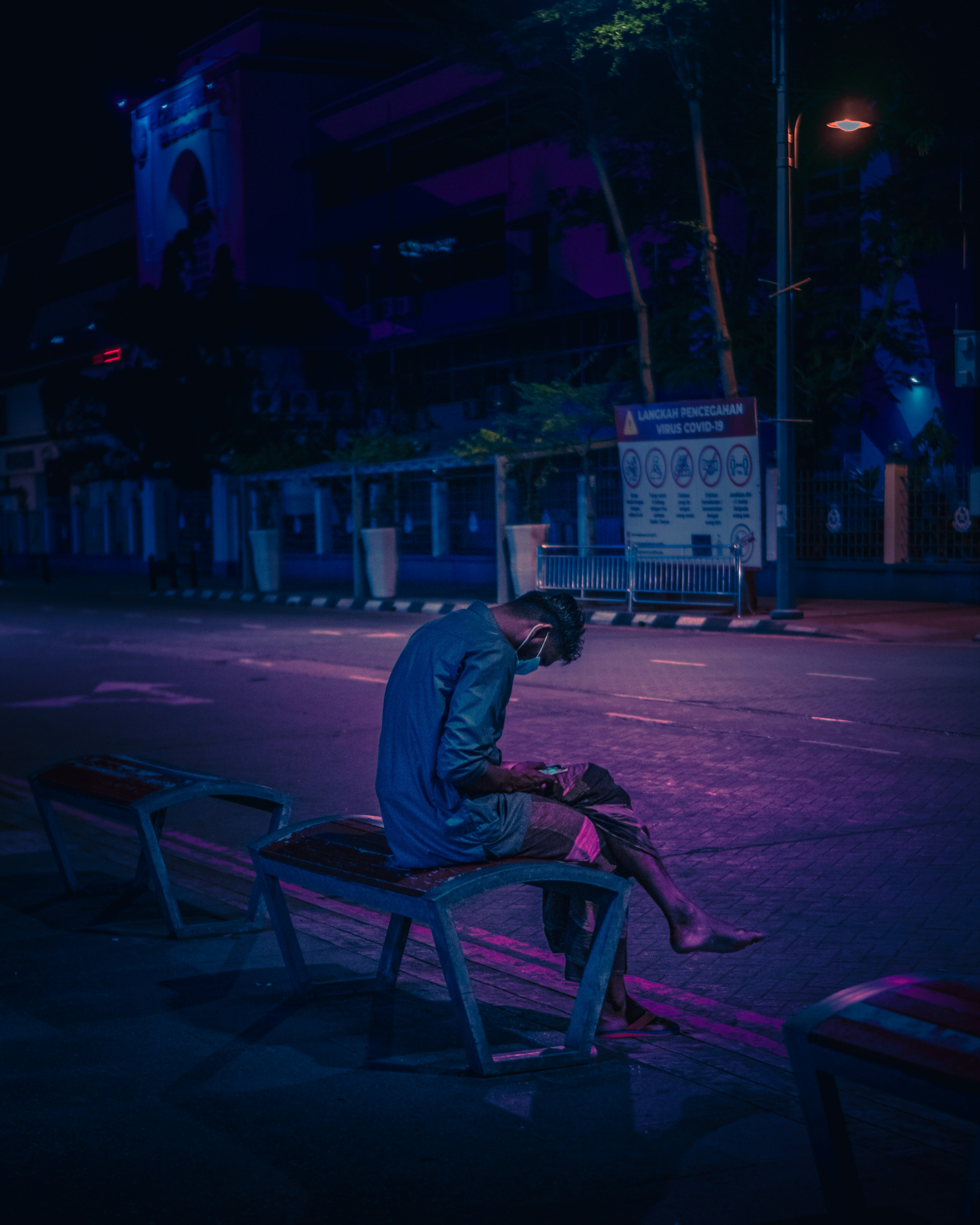 man in blue shirt sitting on brown wooden chair during night time