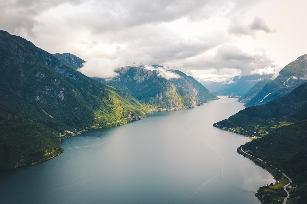 green and white mountains beside lake under white clouds during daytime