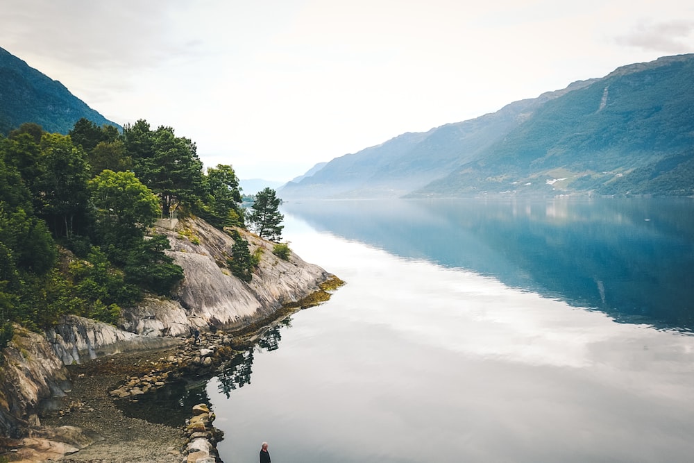 person in black jacket sitting on rock near river during daytime