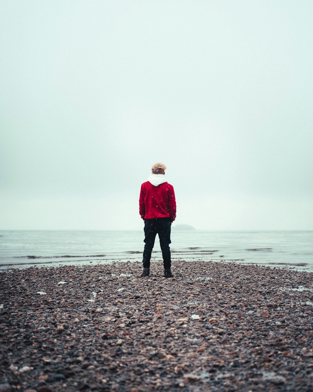 woman in red jacket standing on beach