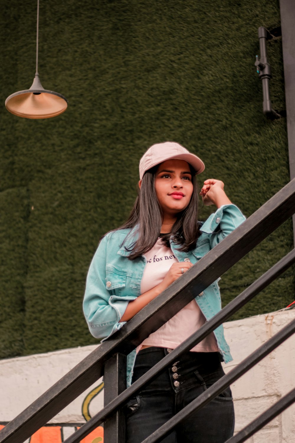 woman in blue denim jacket and brown hat standing on stairs