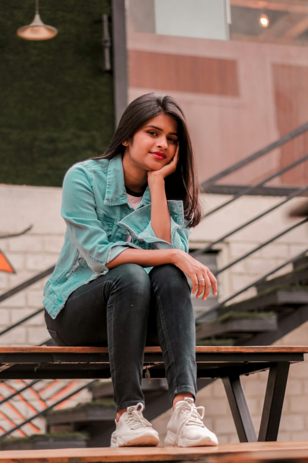 a woman sitting on a bench with her hand on her chin