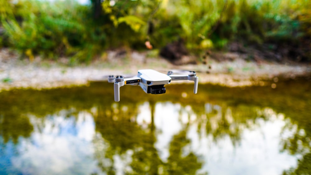 drone branco voando sobre o lago durante o dia