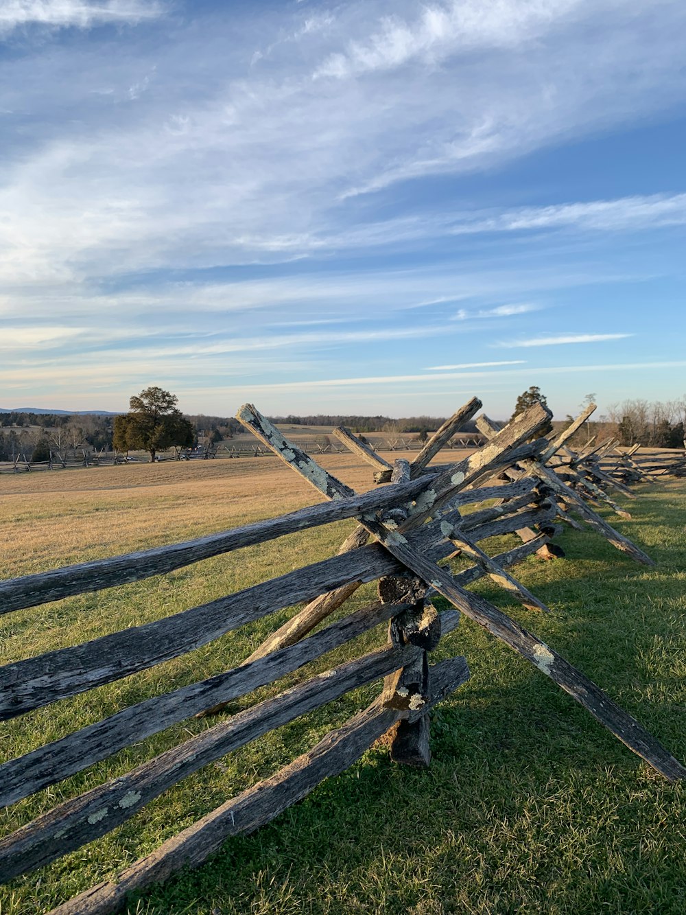 brown wooden fence on brown field under white clouds during daytime